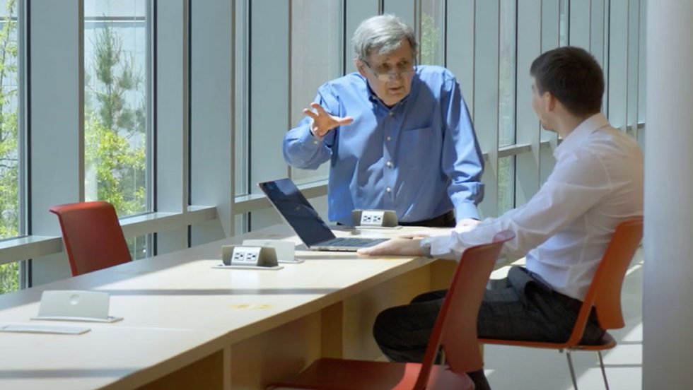 David Machlis, PhD leaning over a table while working with a student at Adelphi University