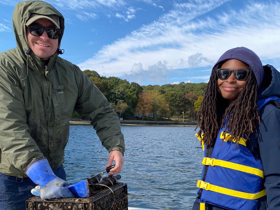 Two people on a boat on the Cold Spring Harbor wearing life vests