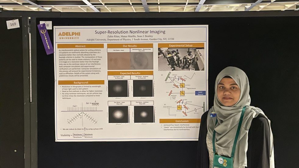 Zahin Ritee standing in front of a research poster for her research in physics.