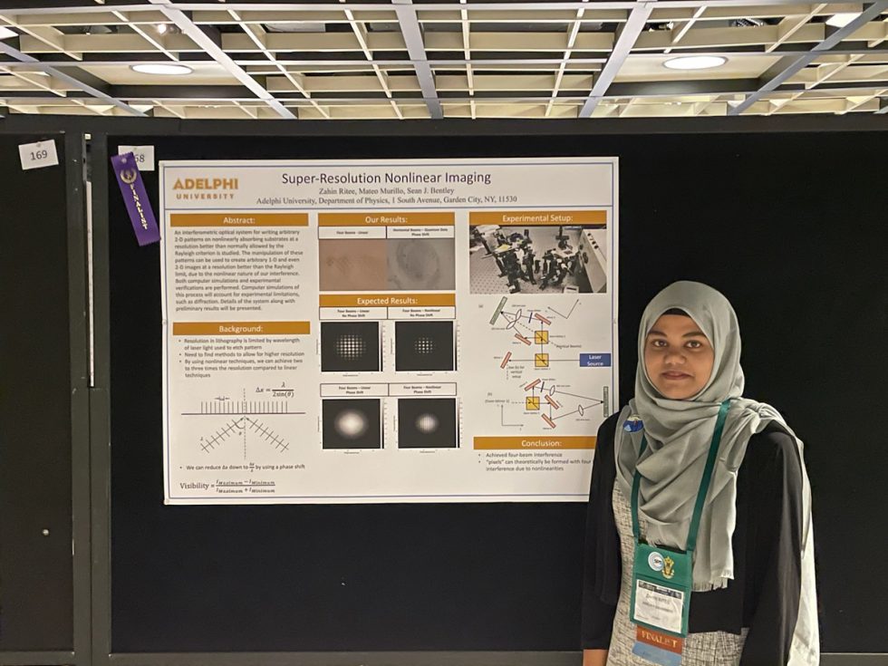 Zahin Ritee standing in front of a research poster for her research in physics.