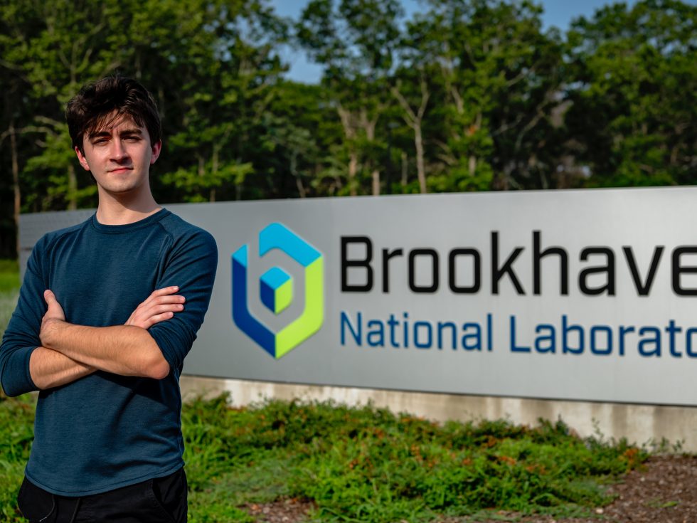 Edward Jansen standing in front of the Brookhaven National Labs sign