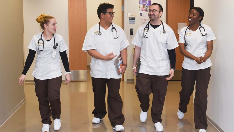 a diverse group of Adelphi Nursing students walking down a hallway together