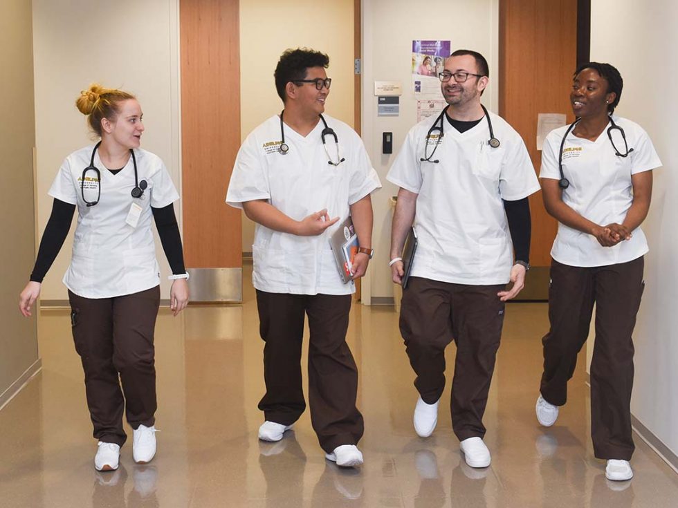 a diverse group of Adelphi Nursing students walking down a hallway together