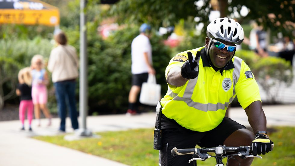 Adelphi University safety office gives peace-sign up while riding on a bike patrol on campus.