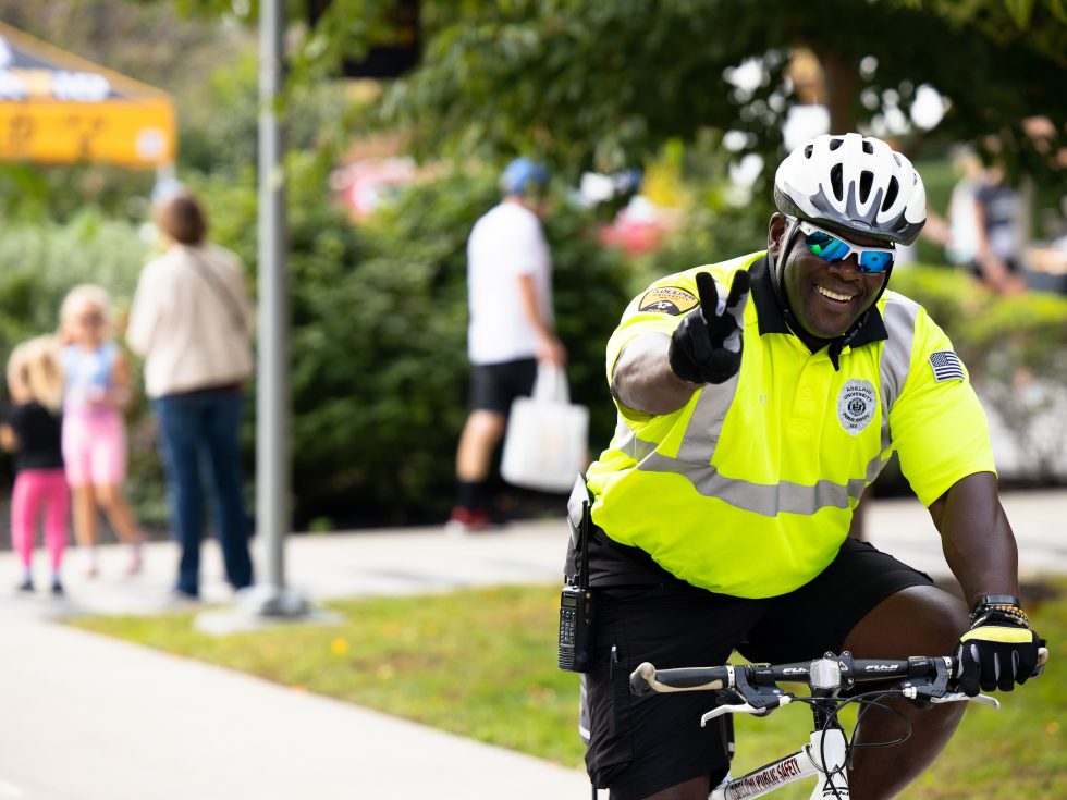 Adelphi University safety office gives peace-sign up while riding on a bike patrol on campus.