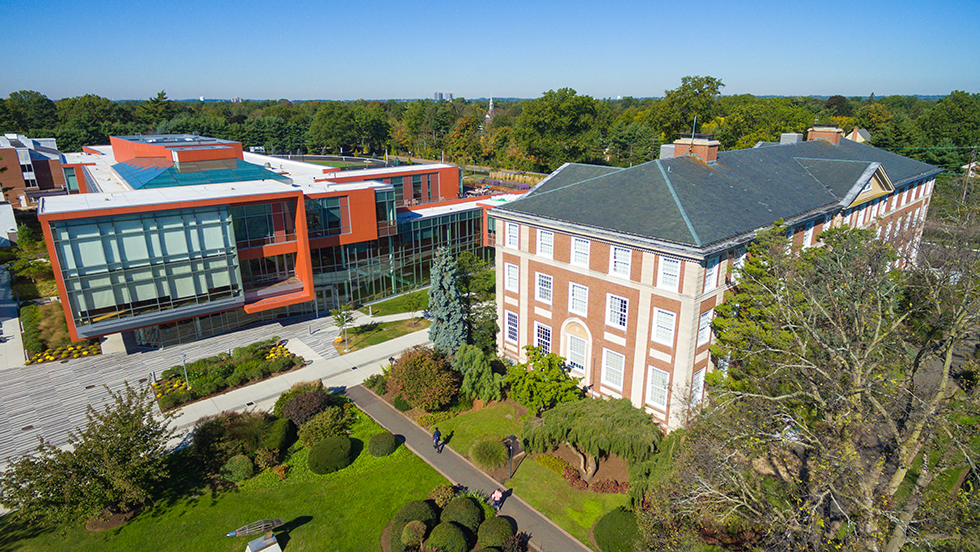 Two buildings next to each other surrounded by grass and trees. 