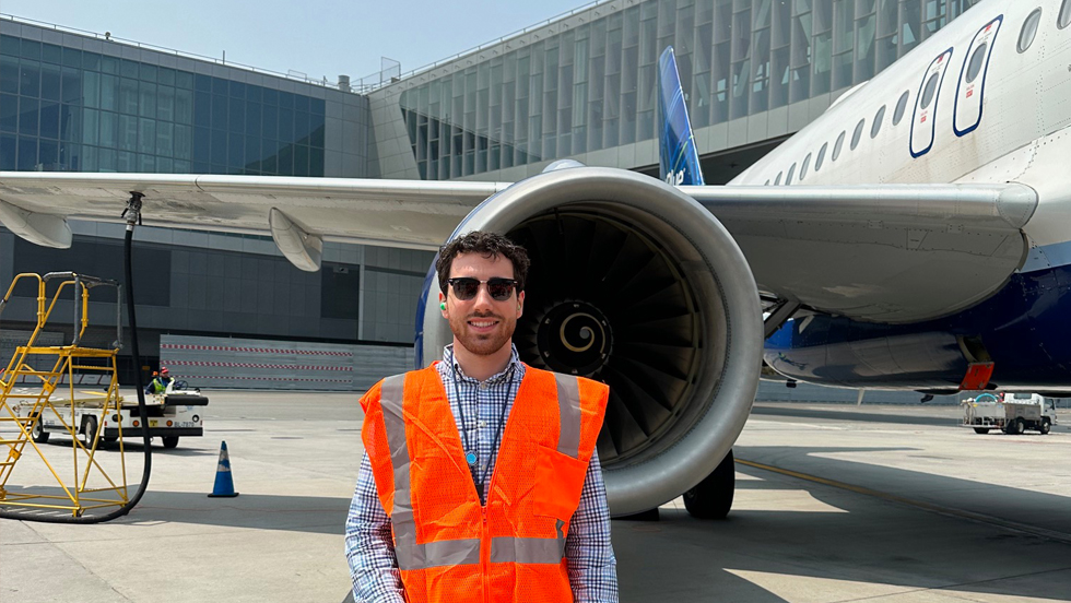 Anthony Lettiere '23 standing in front of a JetBlue engine wearing a safety vest.