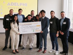 Group of about ten men and women posing with a large check.