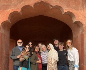 10 people of various ages and backgrounds are standing in front of an arched doorway in Morocco.