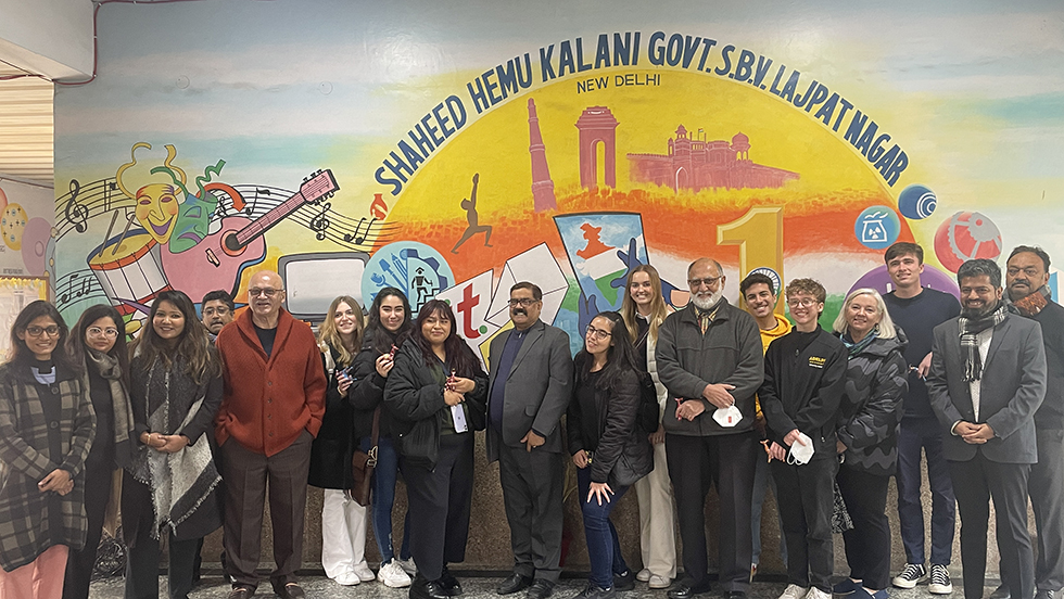 A group of people stand in front of a mural that reads "Shaheed Hemu Kalani Govt. S.B.V. Lajpat Nagar"