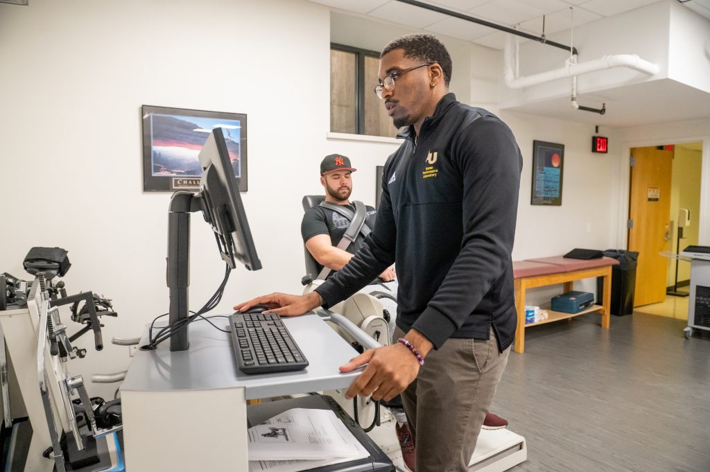 Adelphi health sciences student working at a computer in the exercise lab on campus.