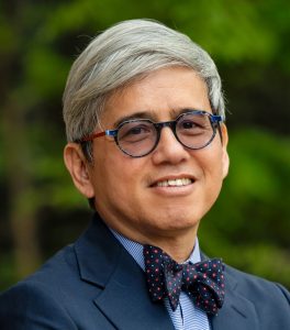 Portrait of Dr. Rozario. He is wearing a blue suit and bow tie.