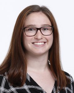 Headshot of woman with red hair in glasses against a white background