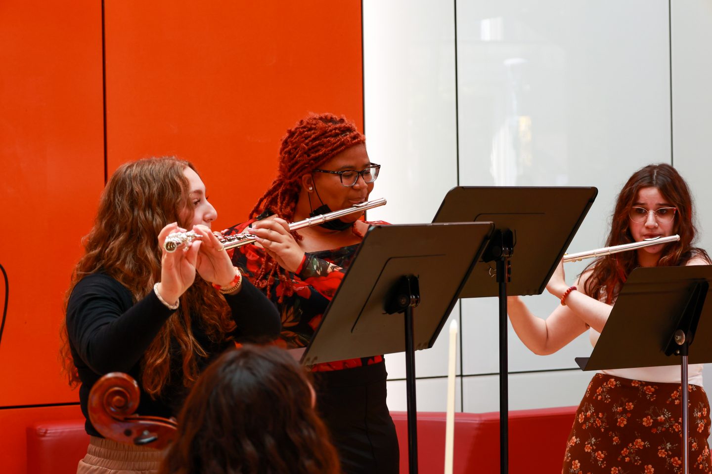 Three women behind music stands playing flutes