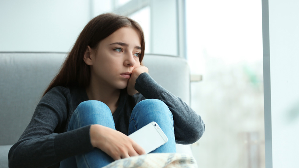 A girl sitting on a couch holding a phone