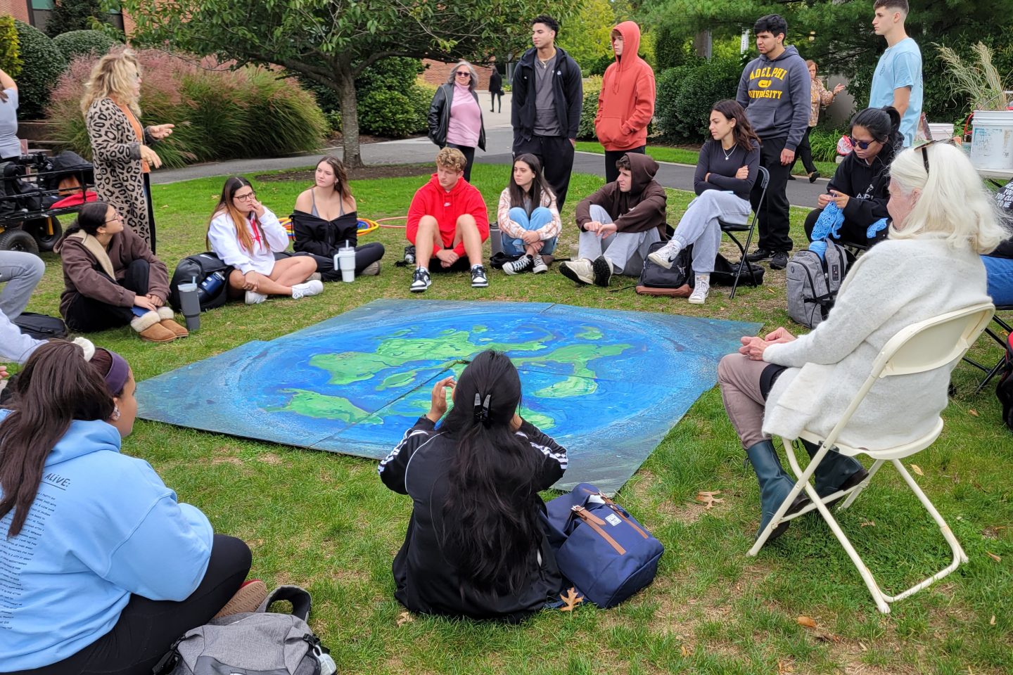 A group of people in a circle surround a painting of a globe.