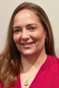 A portrait of Denise Hallinan, wearing a red dress and pendant.