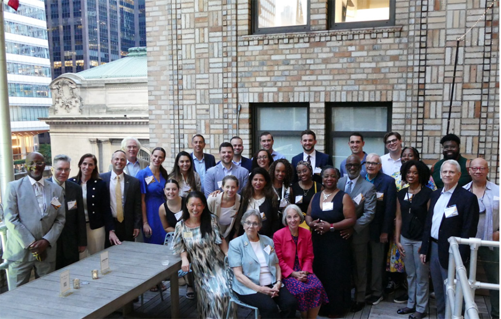 Group photo of men and women in a outside on a rooftop.