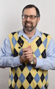Stephen Shore, in an argyle vest and smiling with his hands clasped.