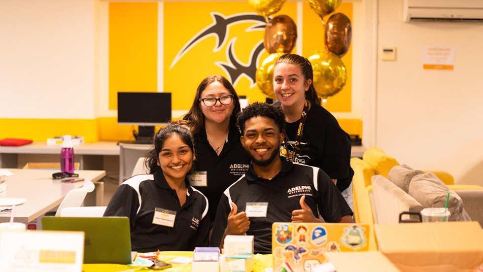 Students in front of a laptop, smiling.