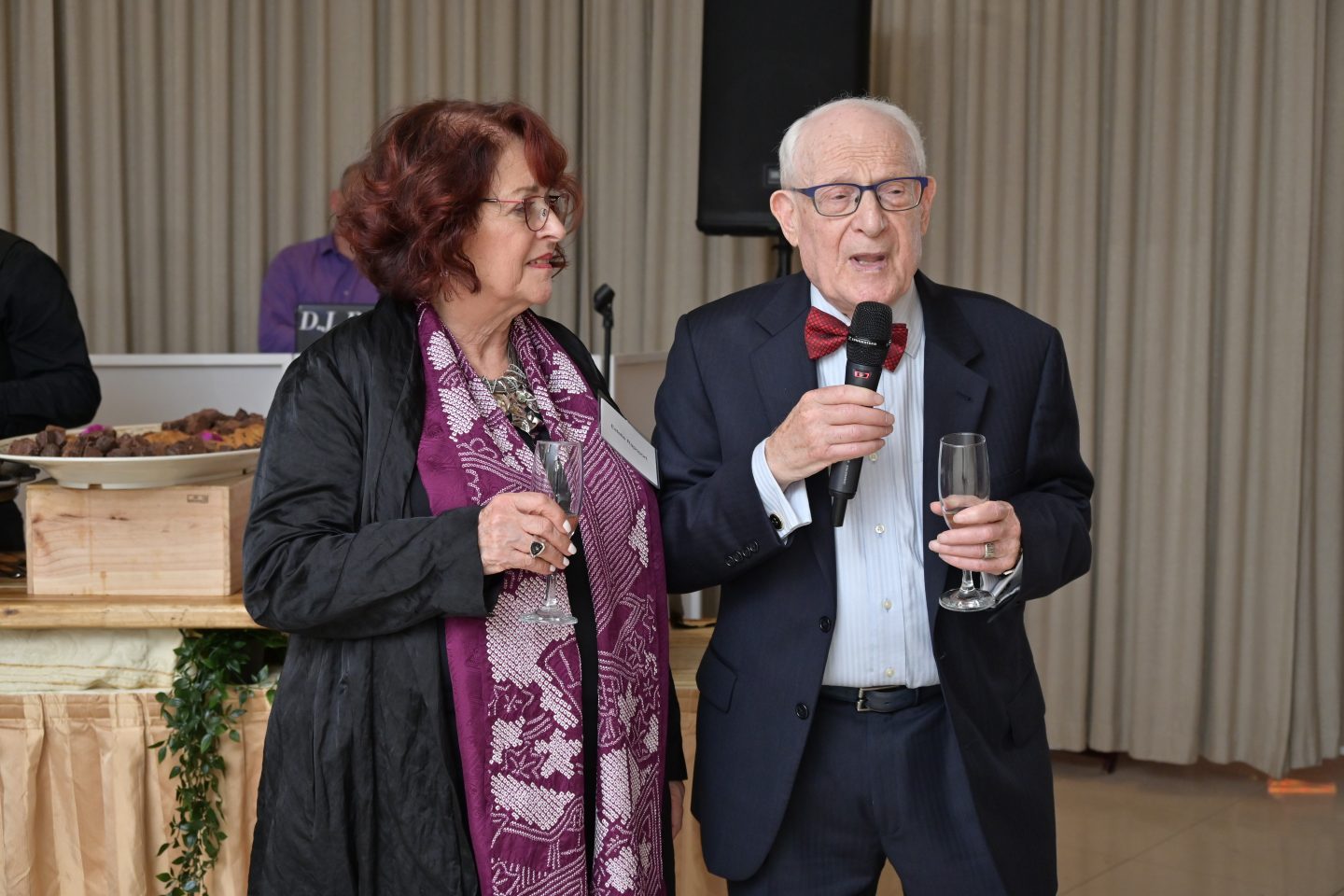 Women is purple dress and man with a microphone