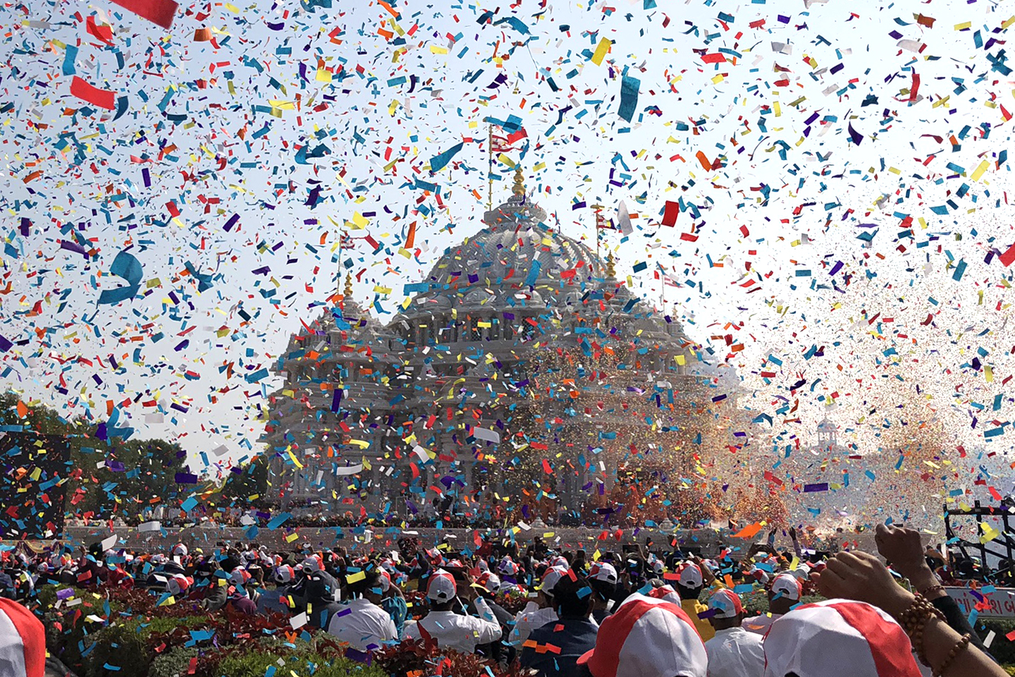 Large crowd faces a temple. Confetti is scattered across the scene.