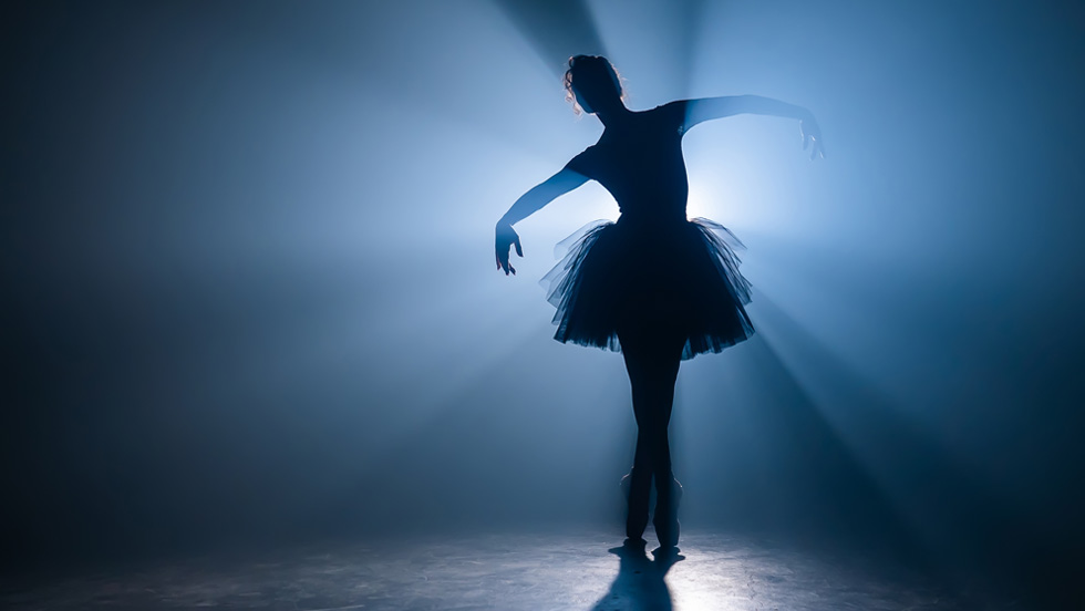 A solo ballet dancer's silhouette is outlined amid white and shades of blue.
