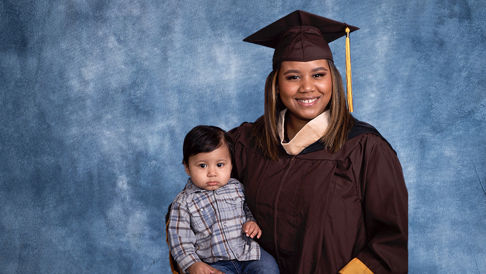 Martinez in her Adelphi cap and gown, holding her son, Kairo.