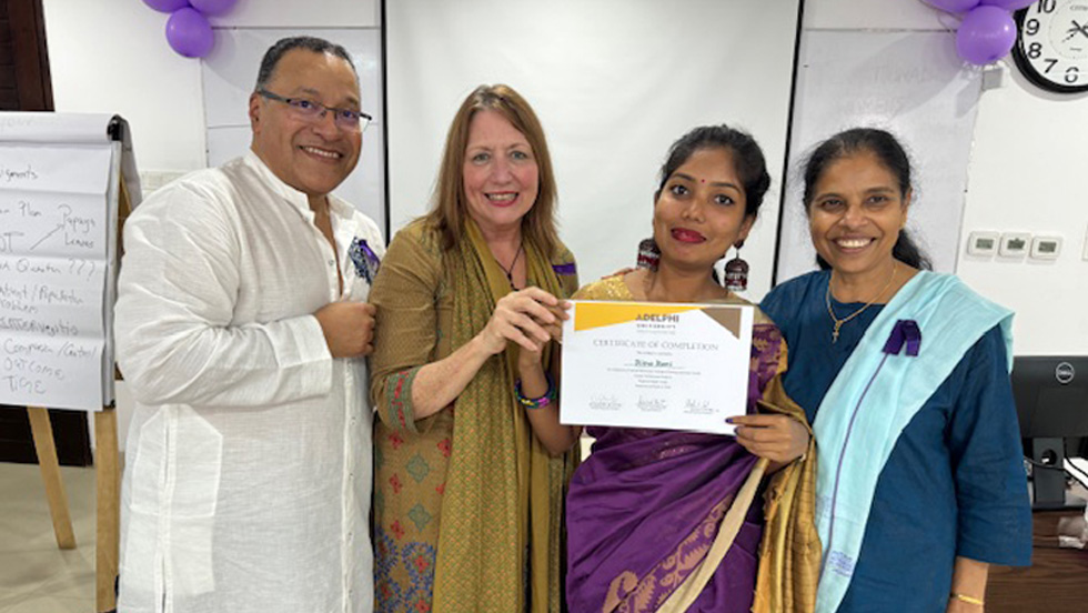  A male with eyeglasses and three females -- one holding a certificate -- are wearing traditional Bangladeshi apparel.
