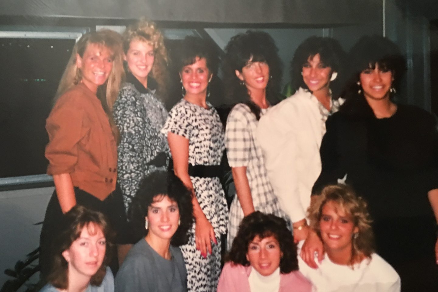 Group of 10 women, all smiling at camera, six standing and four sitting down