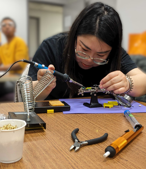 Grace Hu, an Adelphi student soldering a switch for an assistive technology toy drive.