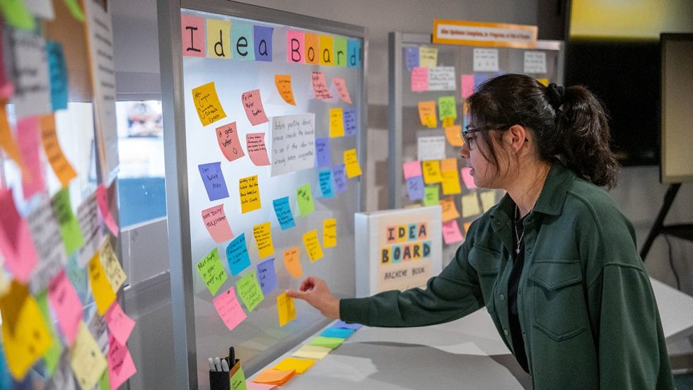 A student adds to the dozens of sticky notes on an idea board at the Center.
