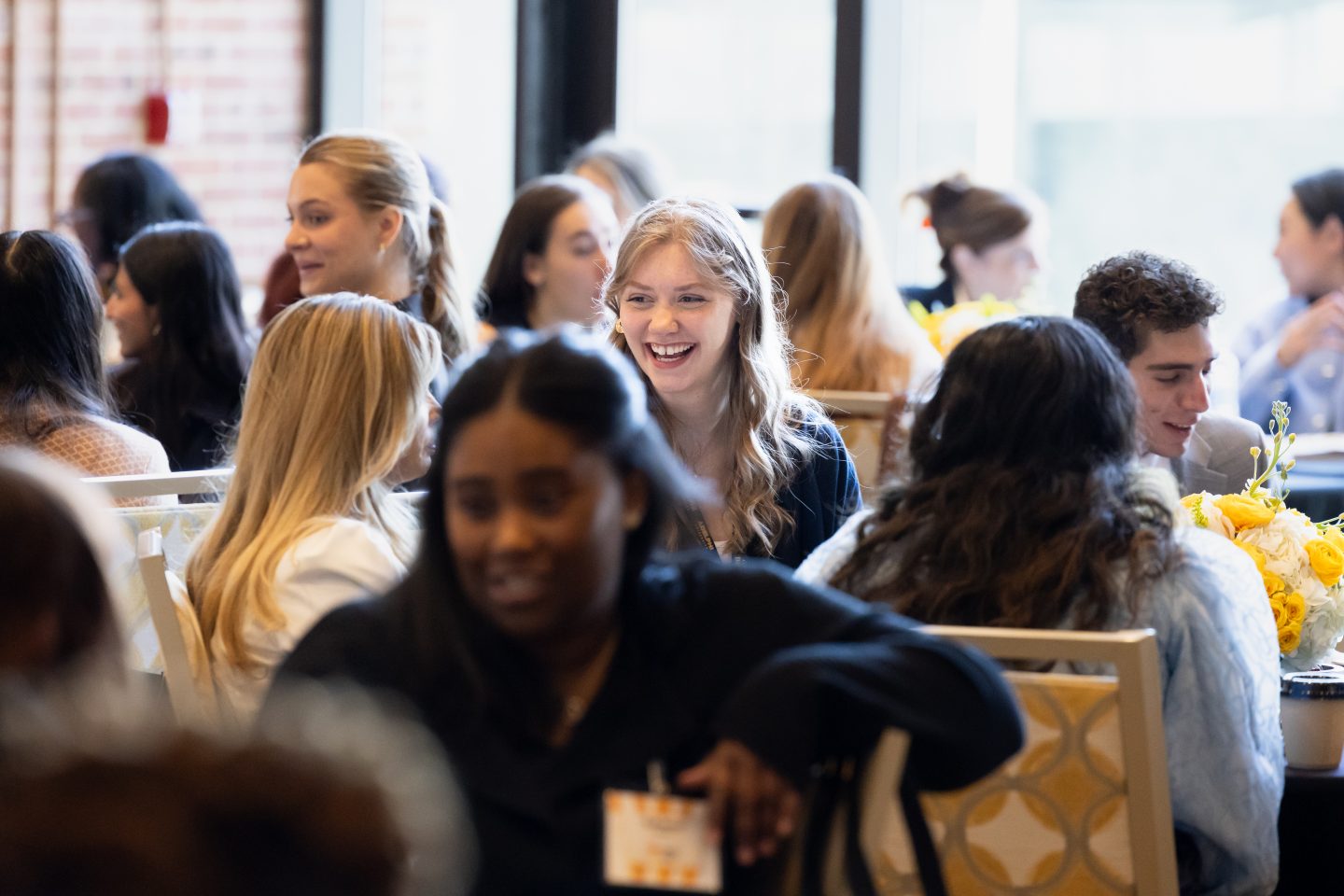 A large group of men and women attendees talking and laughing at brunch