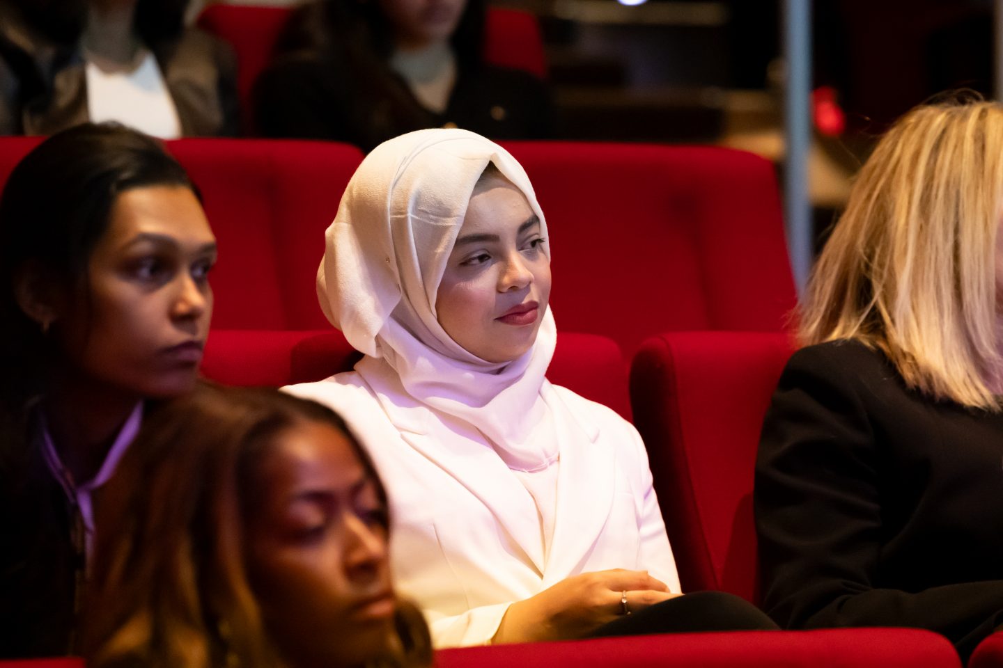 Several seated participants from multicultural backgrounds listen to panelists.