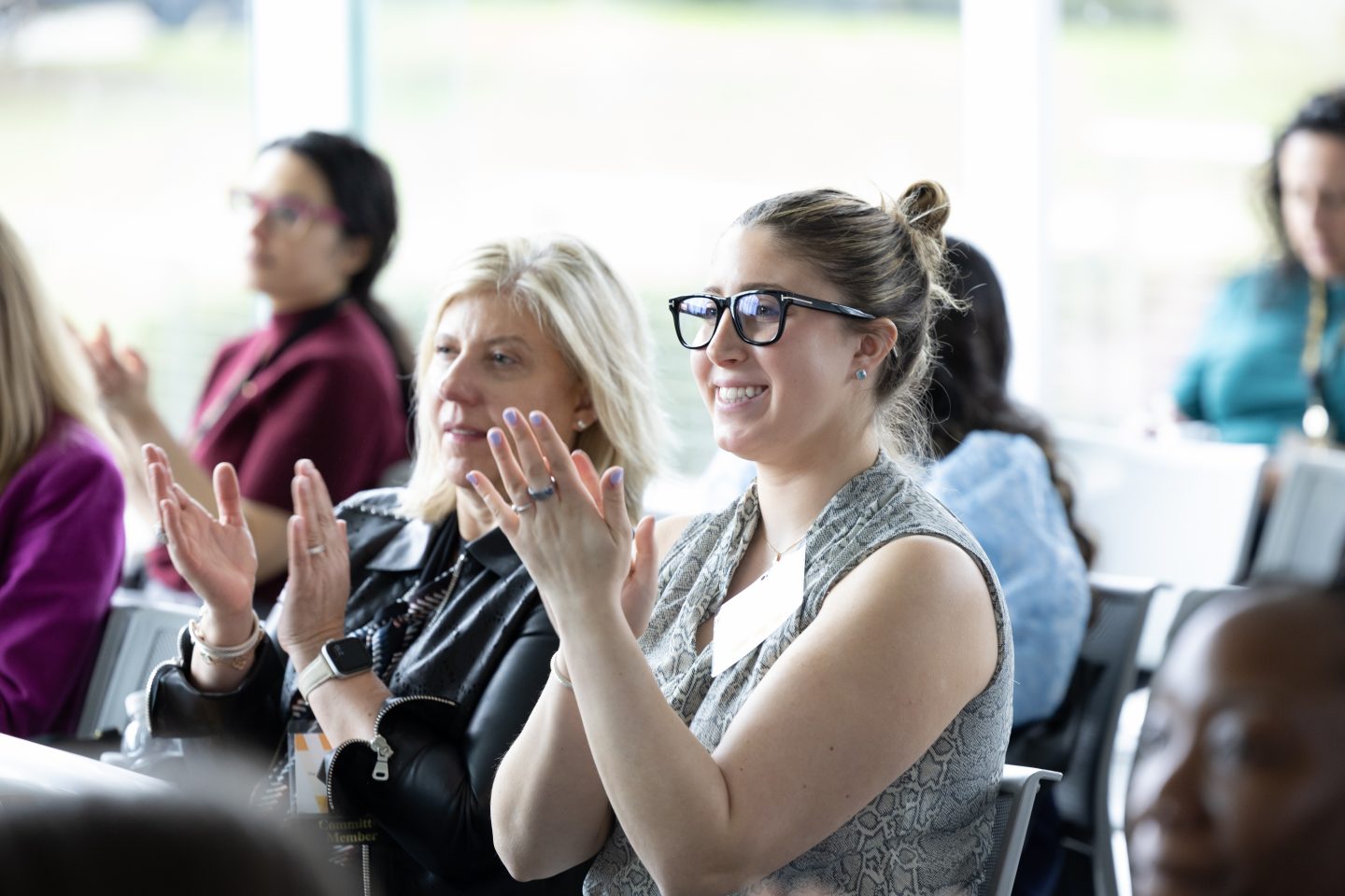 A row of women at the conference applaud a speaker.