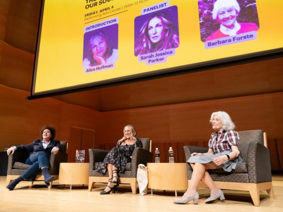 Three women sitting in chairs on a stage.