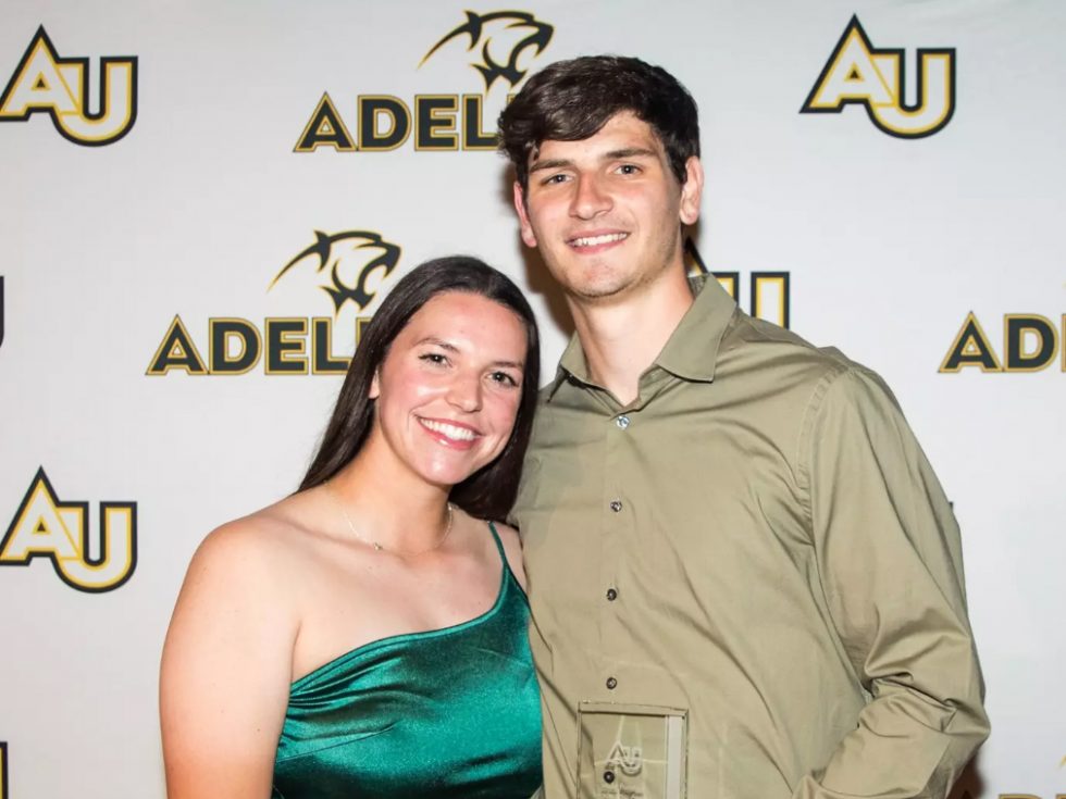 Male and Female student athletes in front of an Adelphi backdrop