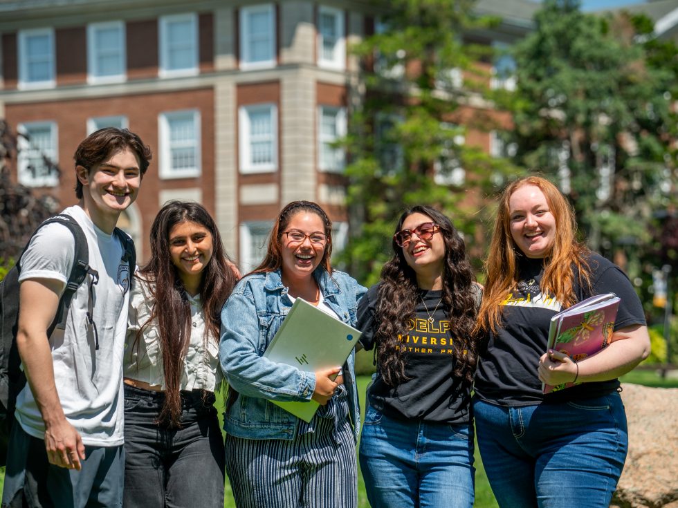 A group of students smiling on Adelphi University&#039;s beautiful campus