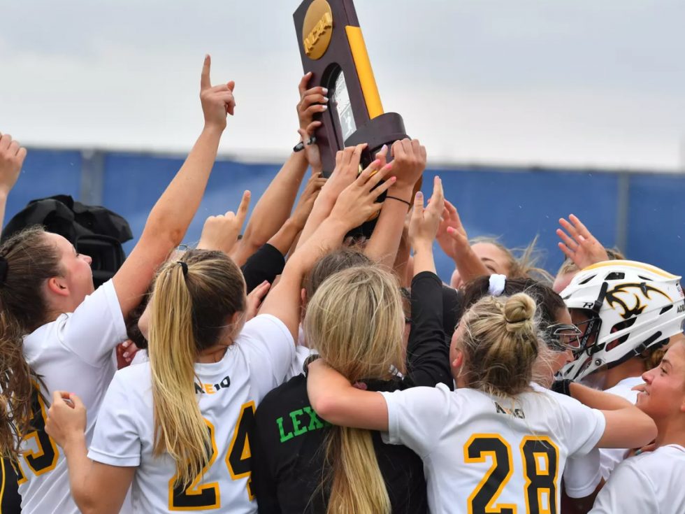 Women&#039;s 2019 Lacrosse team celebrating on field with a trophy