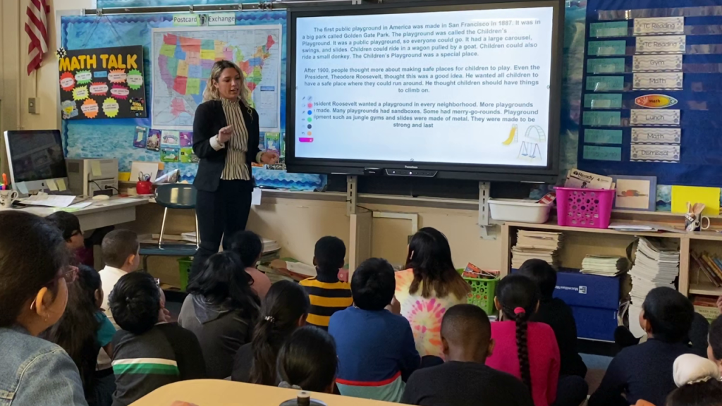 Female student teaching in front of a childrens class.