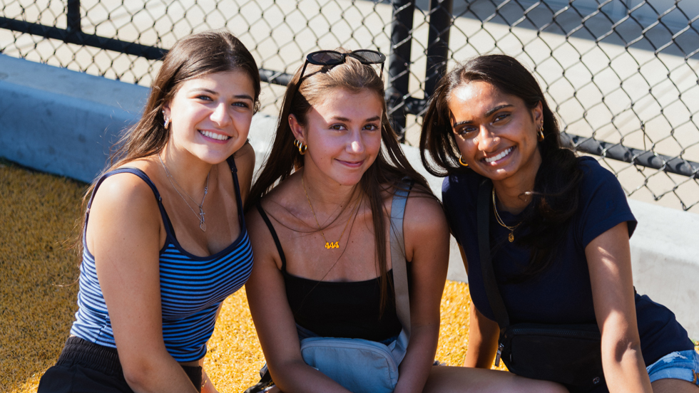 Three student spectators enjoy the games from the sidelines.