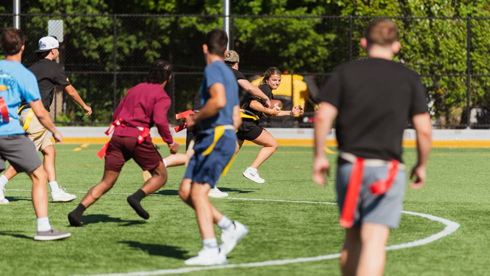 A runner with the football tries to elude seven defenders in a game of flag football held on Adelphi's lacrosse and soccer field.