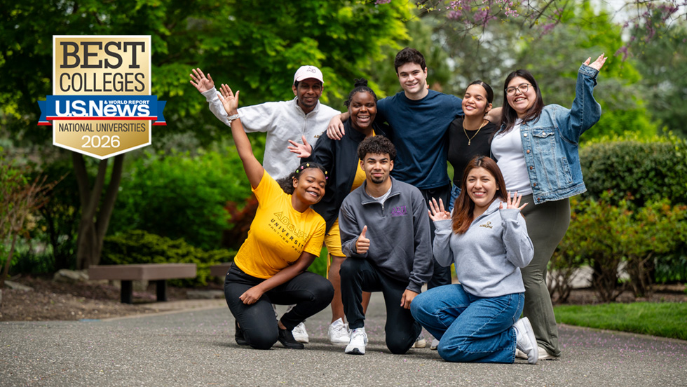 A joyful group of students walking on Adelphi's campus surrounded by trees and greenery