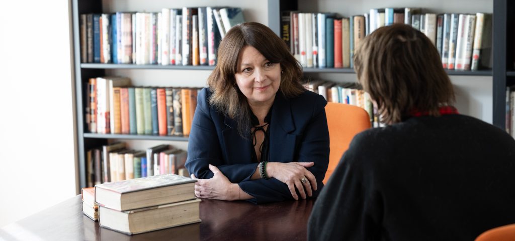 Two women sitting and taling at a table with books