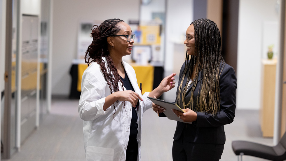 A professor chats with a student in the hallways of the Nexus Building on the Adelphi campus.