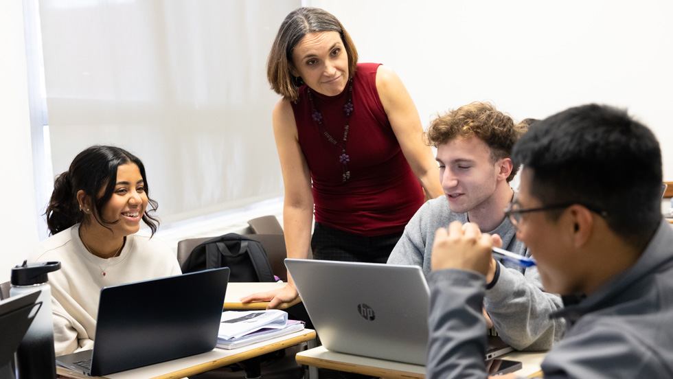 A teacher interacting with smiling students in a classroom setting.