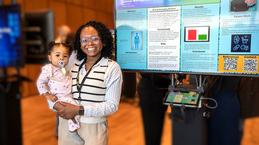 A smiling Black woman wearing glasses and a striped shirt holds a baby with a pacifier in one arm. They are standing in front of a large digital poster board detailing a scientific project.