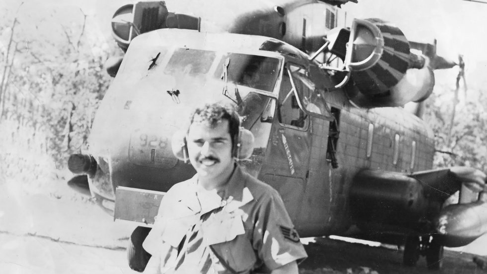 Black and White photo of a man standing in front of a helicopter