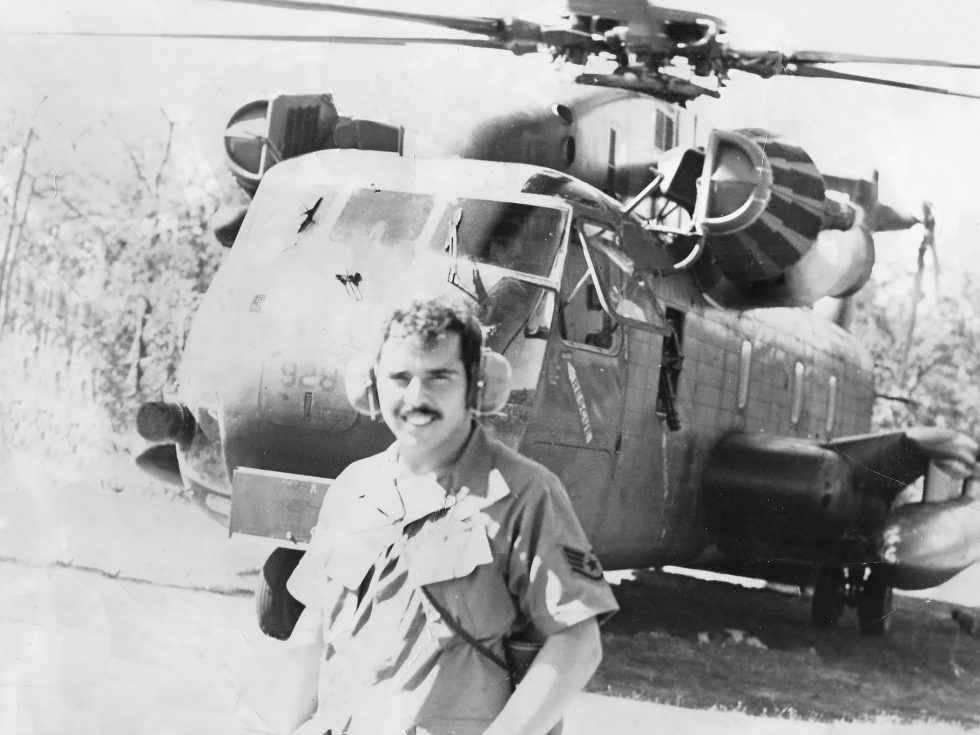 Black and White photo of a man standing in front of a helicopter
