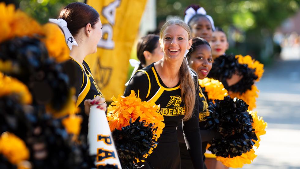 Adelphi cheerleaders line up with their pompoms and megaphones on a beautiful fall day.